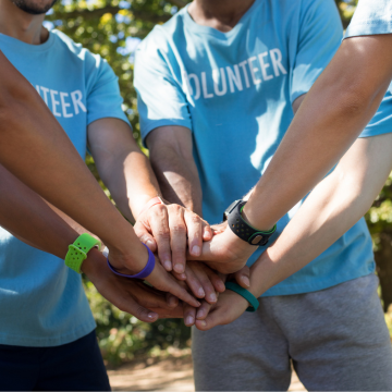 Group of people with their hands in the middle of a circle. 