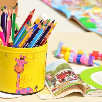 Colored pencils in a yellow tin with a book to the right